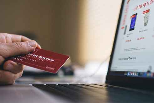 Hand mit Kreditkarte am Laptop